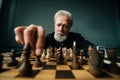 Close-up low-angle view of serious gray-haired mature male performing move with pawn piece on wooden chessboard Royalty Free Stock Photo