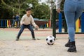 Close up low angle view of young mom and her little son playing soccer together outdoors in a public park Royalty Free Stock Photo