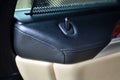 Close-up luxury stitched leather exclusive interior in black and beige colors of a luxury car with a lock button on inside of car