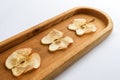Close-up lying diagonally oblong wooden plate with apple chips on white background