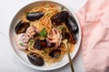 Close up. Macaroni with octopus and tomato sauce. Spaghetti with octopus and mussels in white bowl