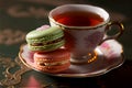 Close up of macarons cakes of different colors served with a cup of hot tea. Rustic culinary concept, generative AI. Royalty Free Stock Photo