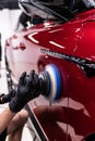 Machine polishing and paint correction on red car body during professional car detailing Royalty Free Stock Photo
