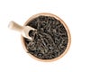 Close up, macro. Flat lay, top view. Wooden bowl with large leaf dried black tea. Isolated on white background. Copy space