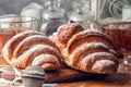 Close up. French croissants with a golden crisp, sprinkled with powdered sugar on top. Next to them is a rosette of jam