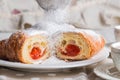 Close up. French croissants on white plate. One of the croissants is cut in half, inside an appetizing juicy strawberry filling. Royalty Free Stock Photo