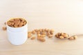 Close up or macro of organic raw peeled almond nuts in cup and spoon with almonds laid around cup on wooden background Royalty Free Stock Photo