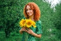 Close up, macro. The red-haired girl in the green vintage dress laughs and looks at the camera. In her hands she holds a bouquet Royalty Free Stock Photo