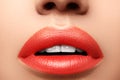 Close-up macro shot of female mouth. Glamour red lips Makeup with sensuality gesture. Orange colour Royalty Free Stock Photo