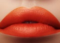 Close-up macro shot of female mouth. Glamour red lips Makeup with sensuality gesture. Orange colour Royalty Free Stock Photo