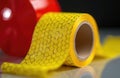 Close up macro shot of yellow reflective tape roll with hexagonal pattern. Red object blurred in background. Safety material for Royalty Free Stock Photo