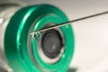 Close-up or macro of syringe needle with a drop at the tip, cap of a vial bottle in the background Royalty Free Stock Photo