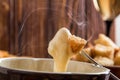 Close up, macro. Traditional french cheese fondue. Crouton dipped into stemy-hot cheese fondue on a long-stemmed fork. Copy space Royalty Free Stock Photo