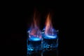 Close up, macro. Two glass glasses with blue alcohol with a flame of burning fire. Black background. Copy space Royalty Free Stock Photo