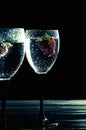 Close up, macro. Wine Glass filled with Sparkling Drink. Strawberries float in the sizzling liquid. Isolated on black background. Royalty Free Stock Photo