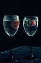 Close up, macro. Wine Glasses filled with Sparkling Drink. Strawberries float in the sizzling liquid. Isolated on black background Royalty Free Stock Photo