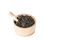 Close up, macro. Wooden bowl with large leaf dried black tea. Isolated on white background. Inside placed measuring spoon