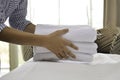 Close-up of maid hands putting fresh white bath towels on the bed sheet. Housekeeper service cleaning in the hotel room. Royalty Free Stock Photo