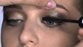 Close up of Makeup artist making professional make-up for young woman in beauty studio. Make up Artist uses mascara to Royalty Free Stock Photo