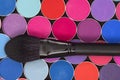 A close-up of makeup brush and colorful eye shadow palette. Bright colorful background. View from above