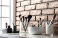 Close-up of makeup brushes in a glass jar on table in stylist room on light background, concept of women\'s cosmetics