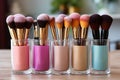 Close-up of makeup brushes in a glass jar on table in stylist room on light background, concept of women\'s cosmetics