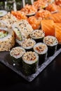 Close up of maki sushi sprinkled with sesame seeds on a stone plate on a dark background Royalty Free Stock Photo