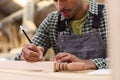 Close Up Of Male Apprentice Working As Carpenter In Furniture Workshop Measuring Wood