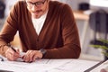 Close Up Of Male Architect At Desk In Office Amending Building Plans