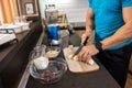 Close up of a male athlete in the kitchen slicing a banana while preparing a shake