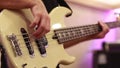 Close-up of male bassist hands playing on electric bass guitar touching strings on rehearsal