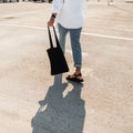 Close-up of a male body in white shirt in red leather sandals in blue jeans with a black fabric bag. Young man in trendy clothes Royalty Free Stock Photo