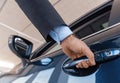 Close up of a male businessman hand opening a car door at the dealership Royalty Free Stock Photo