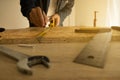 Close-up of male carpenter holding a measure tape in workshop .