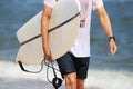 Close up of a male carrying a surfboard walking on the beach Royalty Free Stock Photo