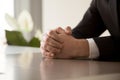 Close up of male clasped hands clenched together on table Royalty Free Stock Photo