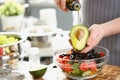 Male cook holding bottle with olive oil, watering avocado with bone, cooking healthy salad