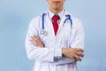 Close-up of male doctor with arms folded having stethoscope on his neck isolated on blue background. Royalty Free Stock Photo