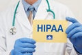 Close-up of a male doctor in gloves holding a sign with the text HIPAA