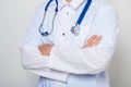 Close-up of a male doctor in a white coat with a stethoscope on his neck, standing with his arms crossed on his chest. Royalty Free Stock Photo