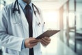 Close-up of male doctor writing on clipboard while standing in hospital corridor, Doctor holding digital tablet at meeting room, Royalty Free Stock Photo