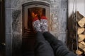 Close up of male feet legs in colored woolen socks are warming near flame, firewood burns in stove, fireplace, cozy winter evening Royalty Free Stock Photo