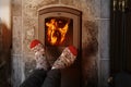 Close up of male feet legs in colored woolen socks are warming near flame, firewood burns in stove, fireplace, cozy winter evening Royalty Free Stock Photo