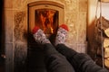 Close up of male feet legs in colored woolen socks are warming near flame, firewood burns in stove, fireplace, cozy winter evening Royalty Free Stock Photo