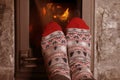 Close up of male feet legs in colored woolen socks are warming near flame, firewood burns in stove, fireplace, cozy winter evening Royalty Free Stock Photo