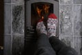 close up of male feet legs in colored woolen socks are warming near flame, firewood burns in stove, fireplace, cozy winter evening Royalty Free Stock Photo