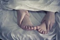 Close up of male and female feet on a bed and couple Royalty Free Stock Photo