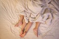 Close up of male and female feet on a bed having sex under sheets in the bedroom