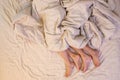 Close up of male and female feet on a bed having sex under sheets in the bedroom