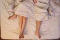 Close up of male and female feet on a bed having sex under sheets in the bedroom